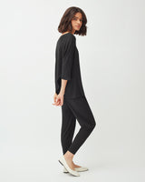 Woman walking in studio wearing a casual outfit and heels.