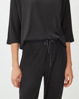 Person in a casual top and pants with hands partially visible