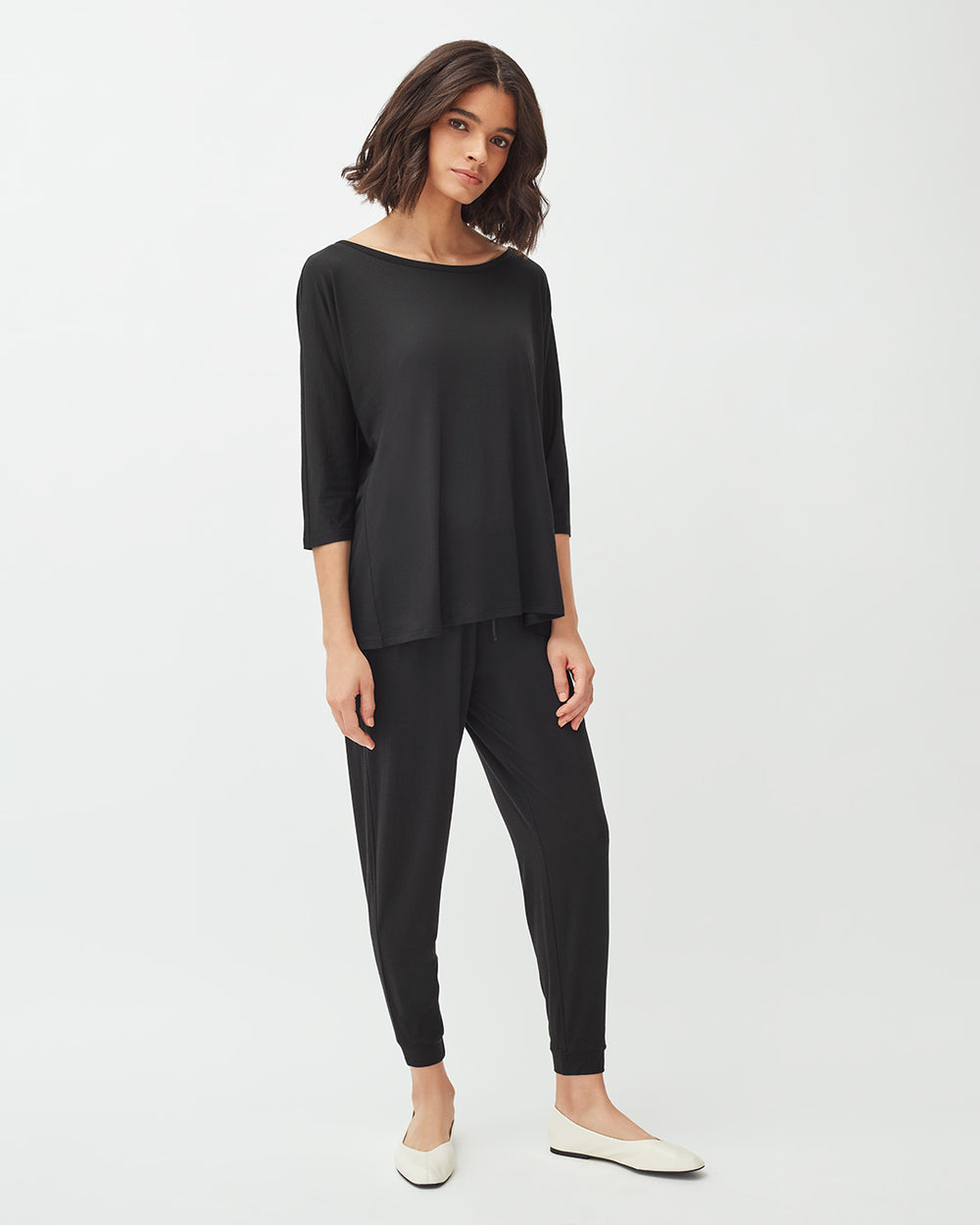 Woman standing in casual outfit with hands slightly raised.