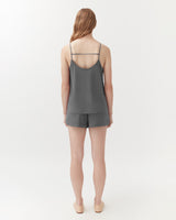 Person standing with their back facing the camera, wearing a tank top and shorts.