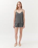 Woman standing in a sleeveless top and shorts, facing forward.