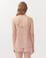 Woman viewed from behind wearing a sleeveless top and shorts.
