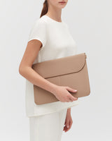 Person holding a large leather laptop sleeve