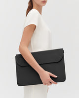 Person holding a large leather laptop sleeve