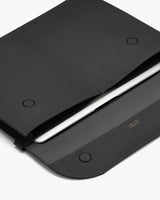 Closed leather folio with a laptop partially visible inside.
