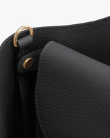 Close-up of a handbag with metal accents and a flap closure.