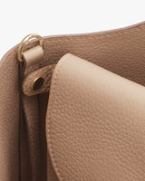 Close-up of a handbag showing partial handle and hardware attachment.
