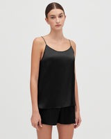 Woman standing in a sleeveless top and shorts, looking at the camera.