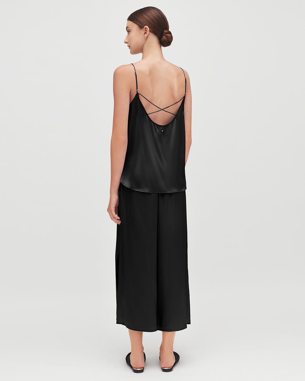 Washable Charmeuse Cropped Wide-Leg Pant Woman standing, wearing a top with crossed back straps and loose pants, viewed from the back.
