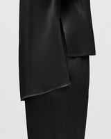 Close-up of a skirt with asymmetric hem over trousers.