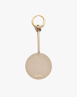 Round keychain with a textured leather finish and a gold-colored ring at the top