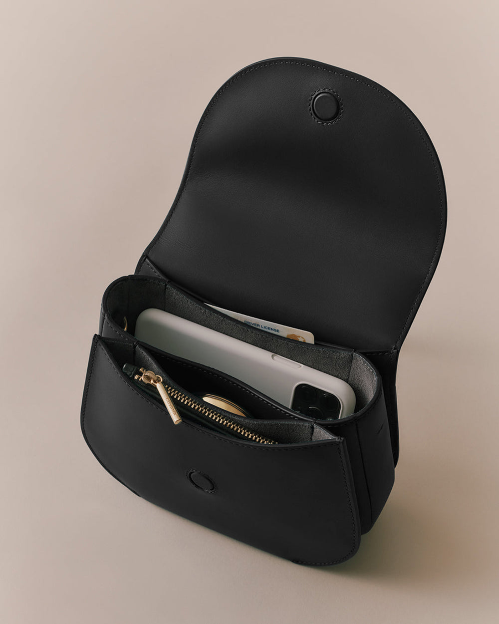 Open handbag with items inside including a phone and a wallet