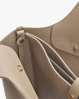 Close-up view inside an open handbag with visible pockets and metal rivets
