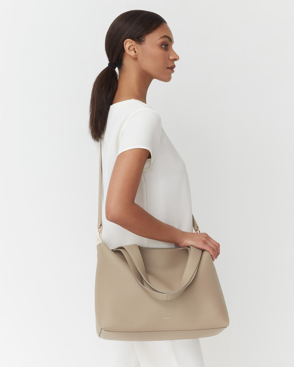 Woman in a top carrying a large shoulder bag, profile view