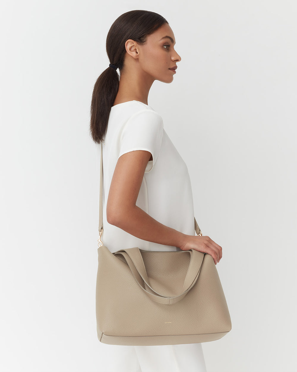 Adjustable Strap Woman in a top carrying a large shoulder bag, profile view