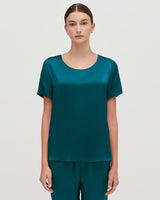 Woman standing straight in a top and pants, facing the camera.