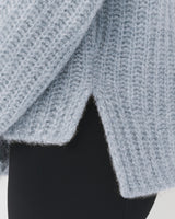 Close-up of a person wearing a knitted sweater and pants.
