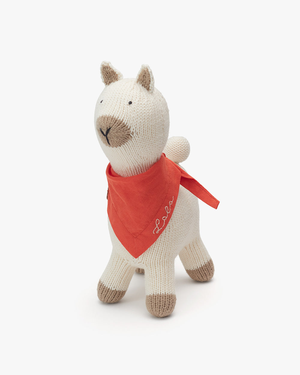 Stuffed alpaca with a bandana around its neck standing upright.