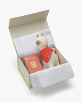 Stuffed alpaca and book in an open box.