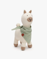 Stuffed alpaca toy with a scarf around its neck standing upright.