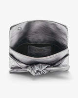 Open metallic clutch bag with a brand label inside.