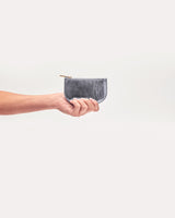 Hand holding a small zippered pouch against a light background