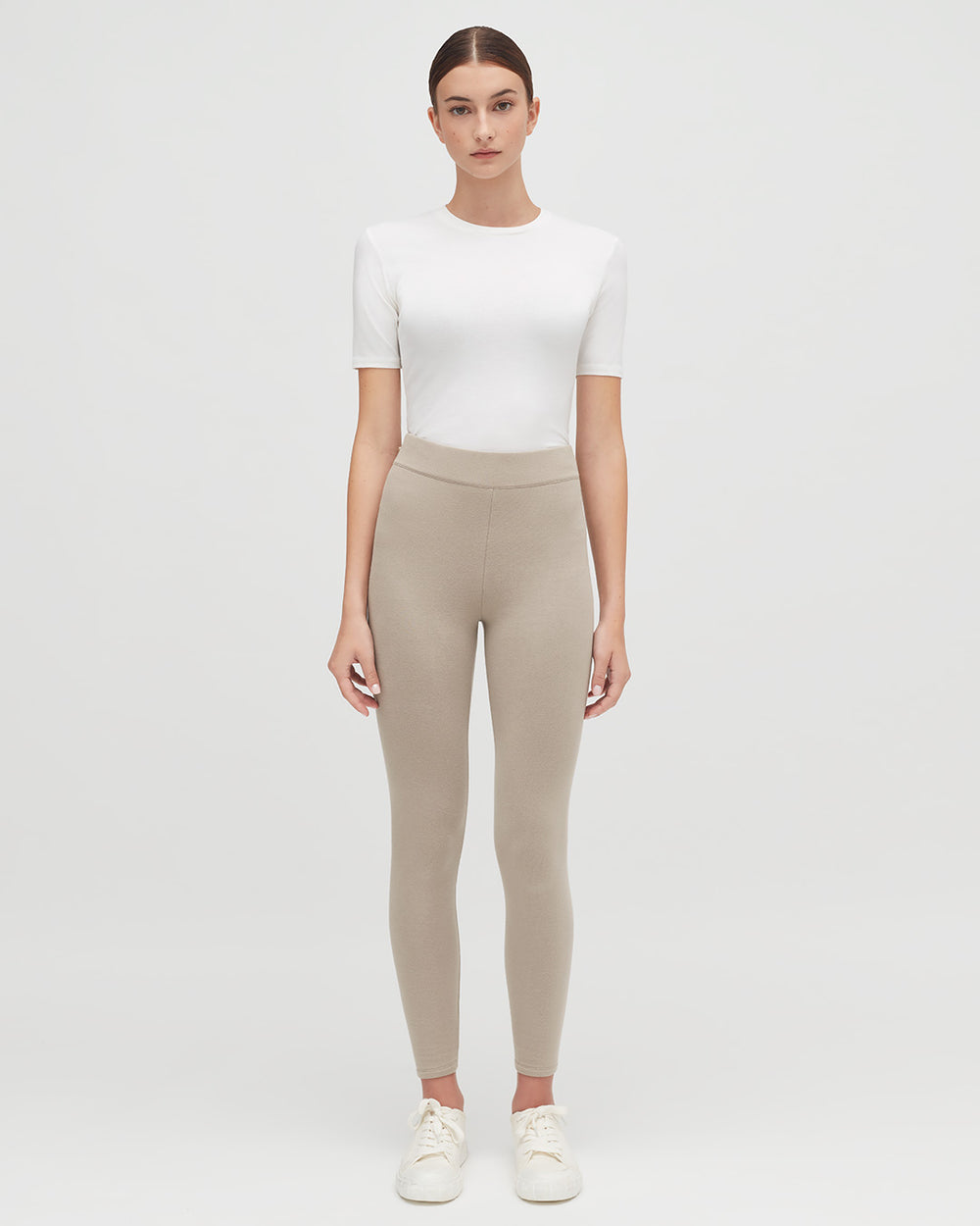 Woman standing in a plain t-shirt and leggings, looking at the camera.