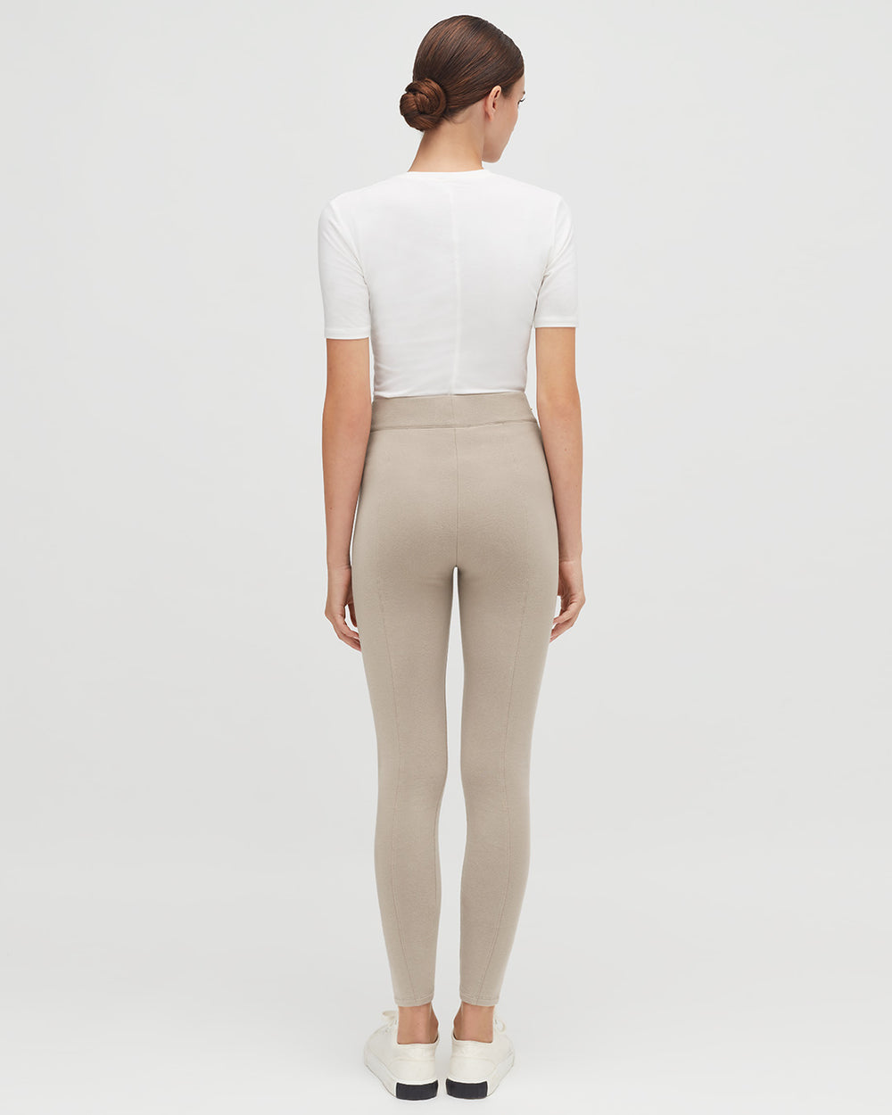 Woman seen from behind wearing a fitted top and leggings, standing upright.