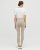 Woman seen from behind wearing a fitted top and leggings, standing upright.