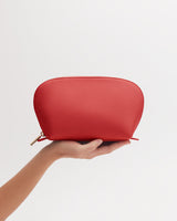 Hand holding a small zippered pouch against a white background.