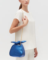 Person in white outfit holding a handbag with a chain strap