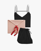 Top, envelope with ribbon, and drawstring bag arranged on plain background.