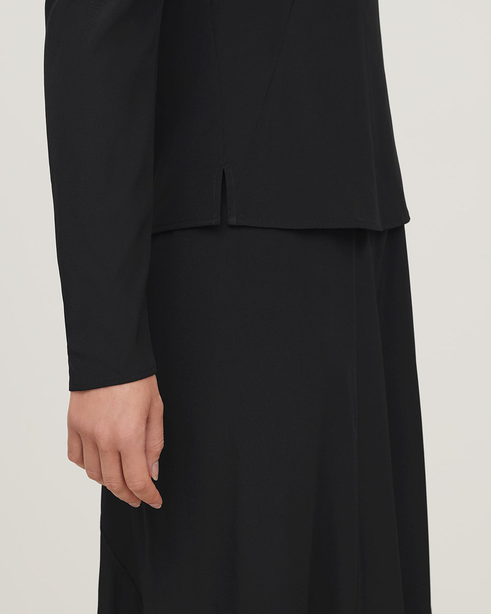 Close-up of a person wearing a long-sleeved top and skirt.