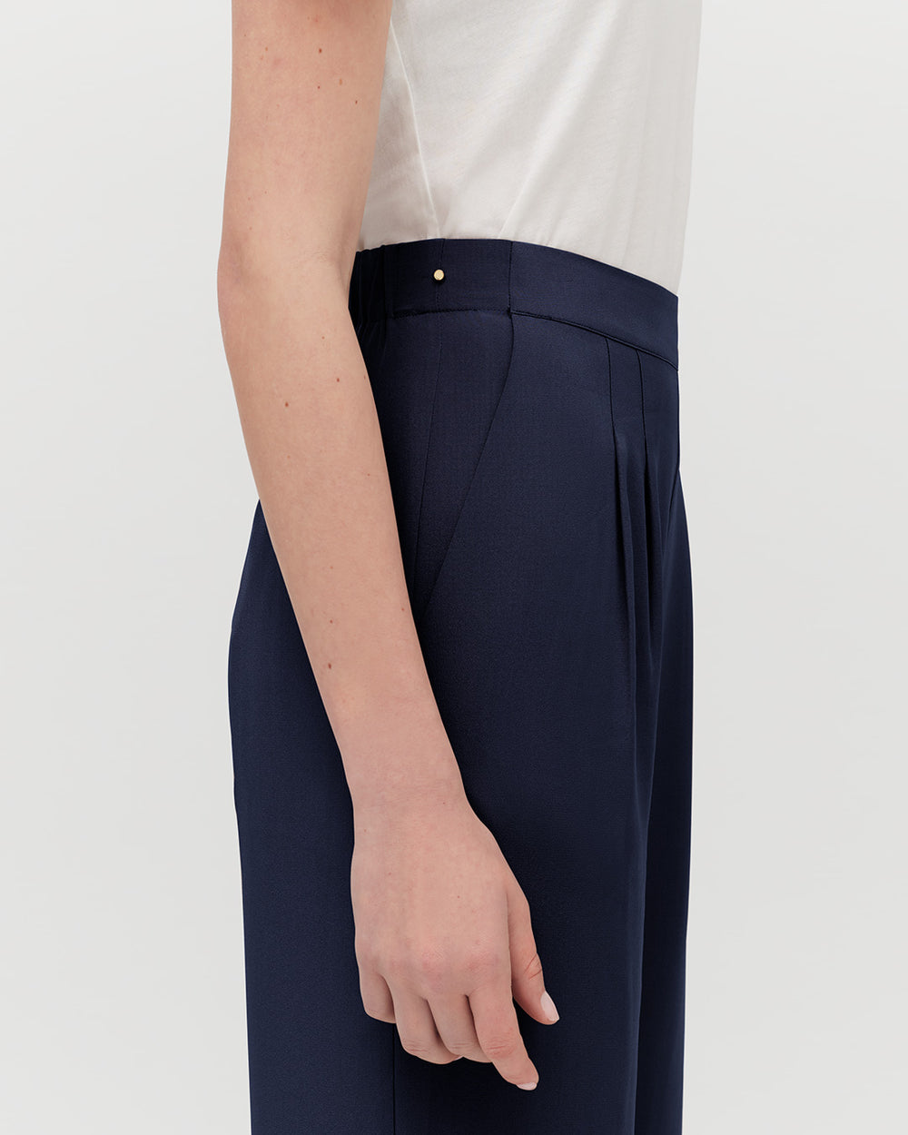 Person standing side view with hand along trouser seam.