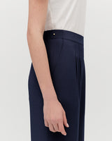 Person standing side view with hand along trouser seam.