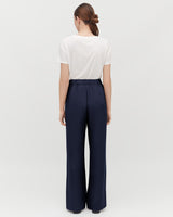 Woman standing with her back facing the camera wearing a T-shirt and wide-leg pants