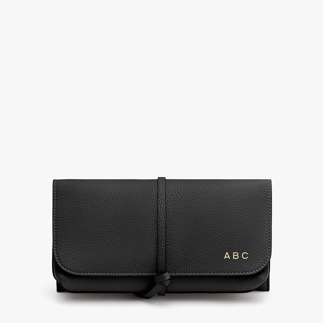 Wallet with a strap closure and monogram initials 'ABC' on front.