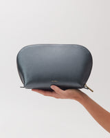 Hand holding a textured zippered pouch with a logo.