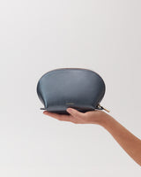 Hand holding a small zippered pouch against a plain background.
