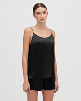 Woman standing and facing forward in a sleeveless top and shorts.