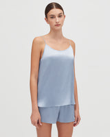 Woman standing and looking at the camera, wearing a top and shorts.