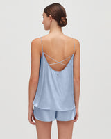 Woman wearing a strappy top and shorts, viewed from the back.