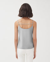 Woman with short hair viewed from the back, wearing a sleeveless top and pants.