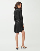 Woman standing and looking over her shoulder in a dress with heels.