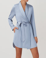 Person in a wrap dress with a belt standing with hand on hip.