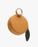 Round textured leather bag with ring handle and leaf accent.