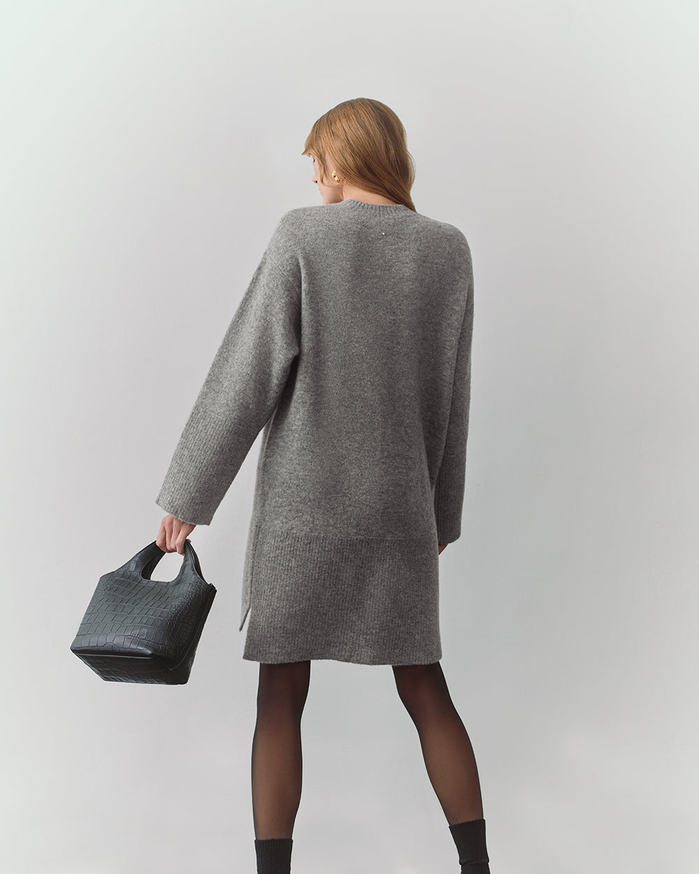 Person in long dress holding a croc-embossed leather handbag