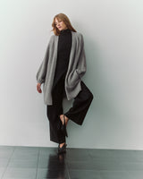 Person wearing long cardigan, black pants, and heels.