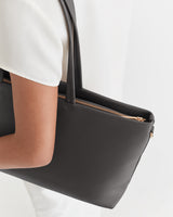 Person holding large handbag with long straps over shoulder