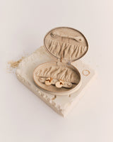 Small jewelry pouch open on a textured surface with earrings inside.